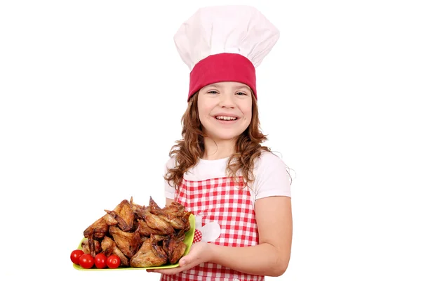 Heureuse petite fille cuisinier avec des ailes de poulet rôti — Photo