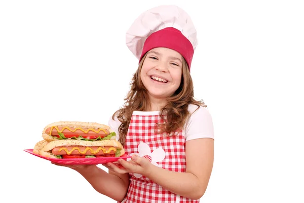 Happy little girl cook with hot dogs fast food on plate — Stock Photo, Image