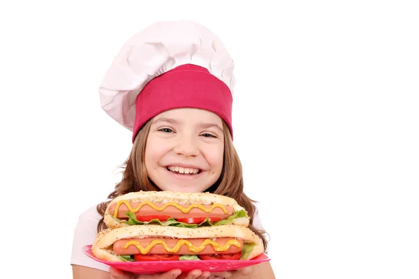 Feliz niña cocinero con hot dogs comida rápida — Foto de Stock