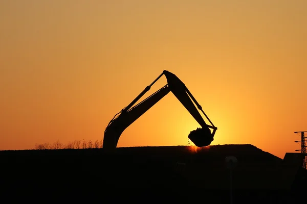 Excavadora trabajando en la silueta del sitio de construcción — Foto de Stock