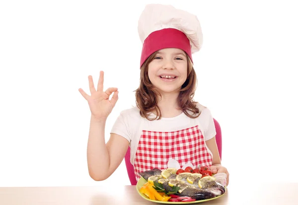 Gelukkig meisje koken met forel en ok hand teken — Stockfoto