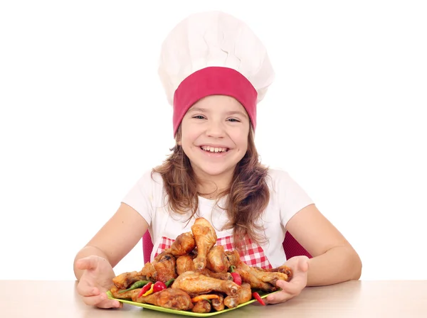 Happy little girl cook with roasted chicken drumsticks on plate — Stock Photo, Image