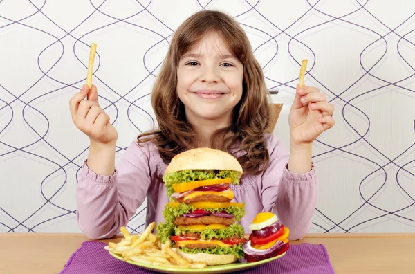 Kleines Mädchen mit großen Hamburgern und Pommes — Stockfoto