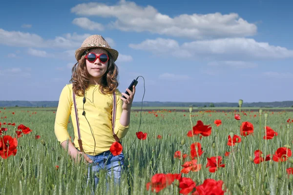 Petite fille écouter de la musique sur le téléphone dans la prairie — Photo