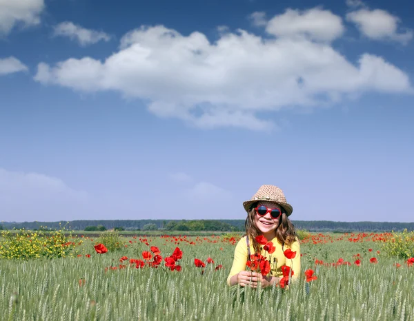 Glückliches kleines Mädchen mit Mohnblume auf der Wiese — Stockfoto