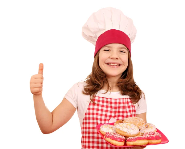 Feliz niña cocinero con donuts dulces y pulgar hacia arriba — Foto de Stock