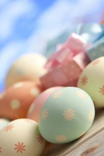 Huevos de Pascua de colores en colores pastel y cajas de regalo en el cielo azul —  Fotos de Stock