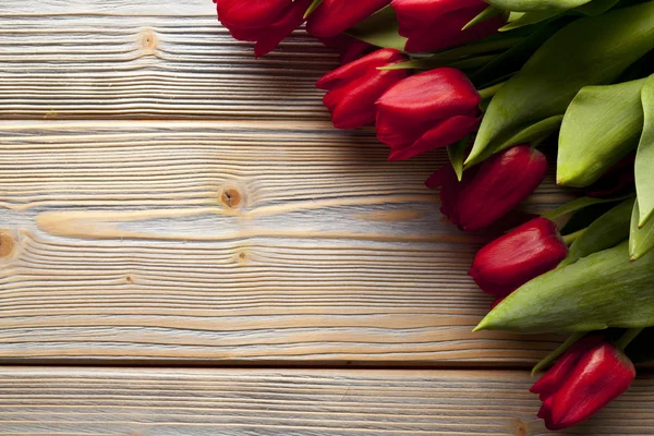 Red tulips on wooden table — Stock Photo, Image