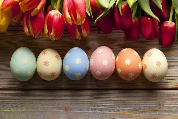 Paaseieren en kleurrijke bloemen op houten achtergrond — Stockfoto