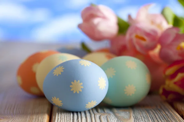 Ostereier in Pastellfarben und bunte Tulpen auf blauem Hintergrund — Stockfoto