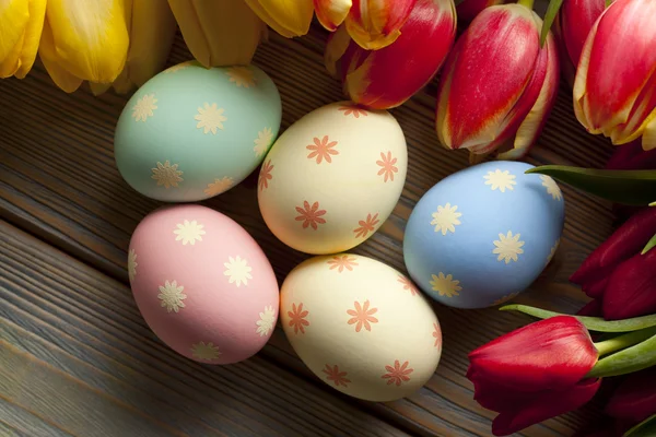 Easter eggs and flowers on wooden background — Stock Photo, Image