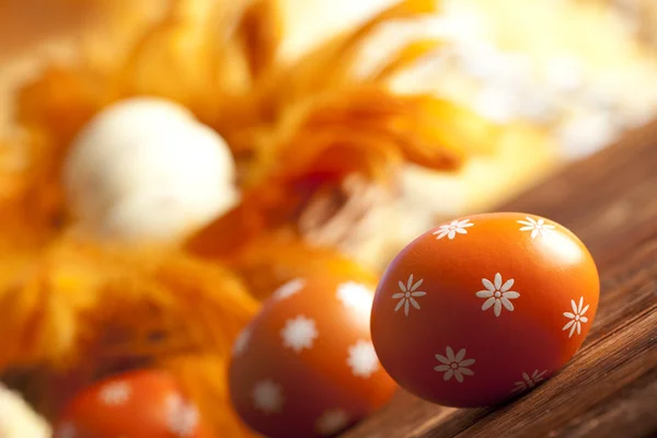 Orange påsk ägg och fjädrar på träbord — Stockfoto