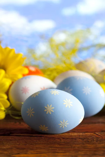 Ostereier und Blumen auf blauem Himmel Hintergrund — Stockfoto