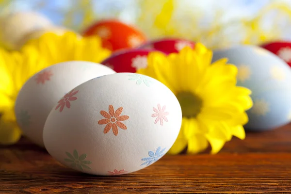 Huevos de Pascua y flores de margarita sobre mesa de madera —  Fotos de Stock