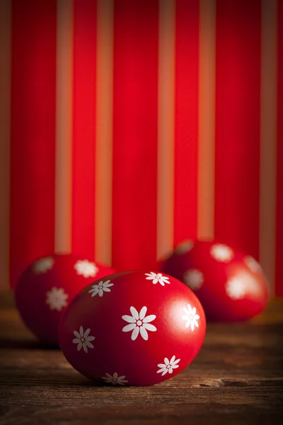 Três ovos de Páscoa no fundo papel de parede vermelho — Fotografia de Stock