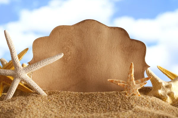 Blanco papier vel en zeesterren op het strand — Stockfoto