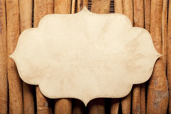 Etiqueta de papel y palos de canela sobre fondo de pared de madera — Foto de Stock