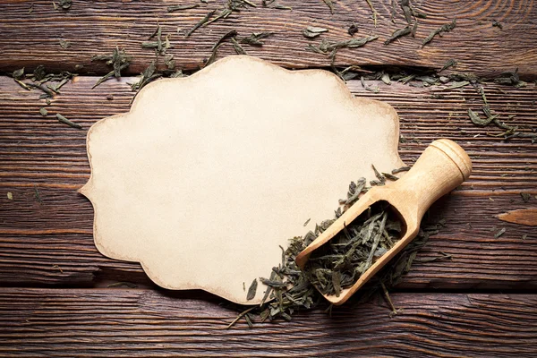 Tarjeta de papel en blanco y hojas secas de té sobre fondo de madera — Foto de Stock