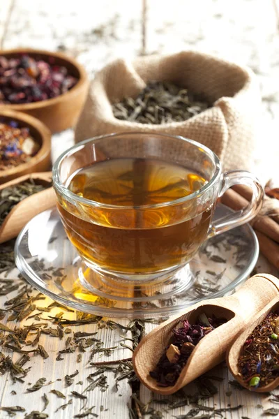 Cup of tea and mix of assorted tea leaves on wooden table