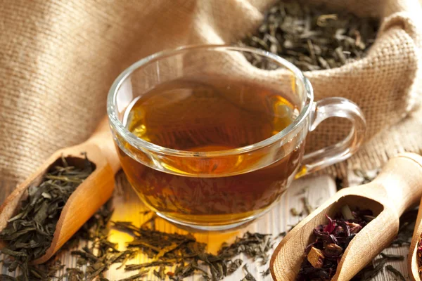 Šálek čaje a čajové listy na dřevěný stůl — Stock fotografie