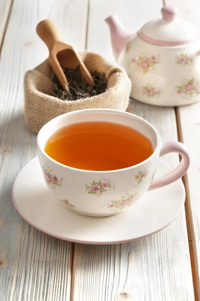 Taza de té, tetera y hojas de té secas en bolsa de yute — Foto de Stock