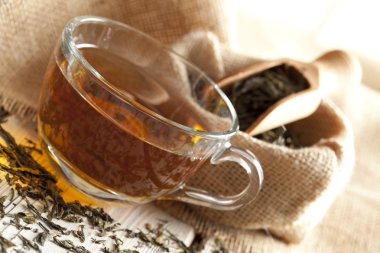 Ahşap masa üzerinde bardak çay ve çay yaprakları