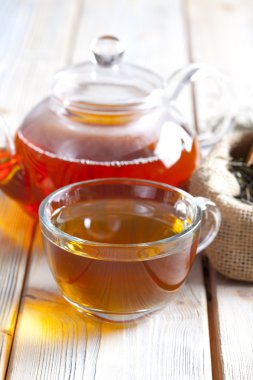 Ahşap plakalar üzerinde bardak çay, çaydanlık ve kuru çay yaprakları