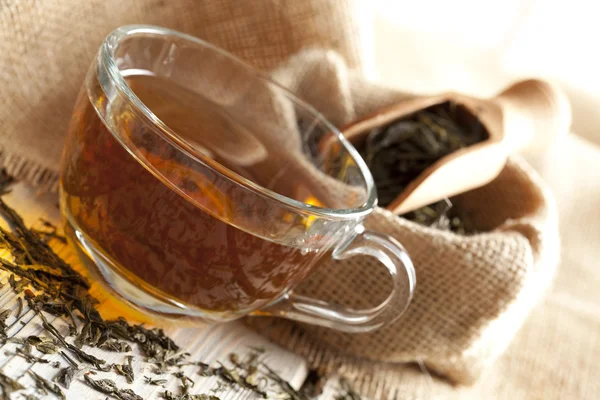 Taza de hojas de té y té sobre mesa de madera — Foto de Stock