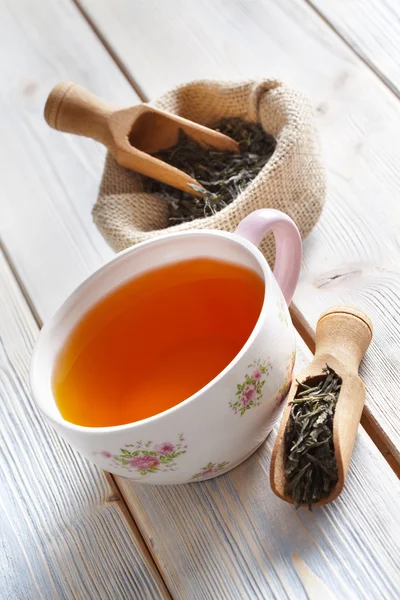 Ahşap masa üzerinde bardak çay ve kuru çay yaprakları