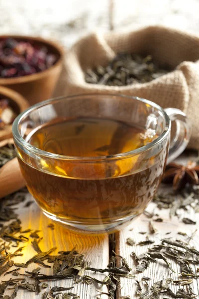 Copa de té y mezcla de hojas de té surtidos en la mesa de madera — Foto de Stock