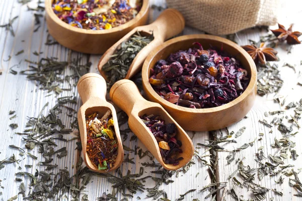 Surtido de hojas de té secas sobre fondo de madera — Foto de Stock