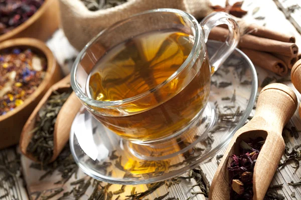Šálek čaje a směsice nejrůznějších čajové listy na dřevěný stůl — Stock fotografie