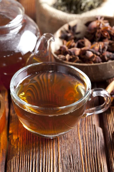 Hojas de té, taza de té y tetera sobre mesa de madera — Foto de Stock