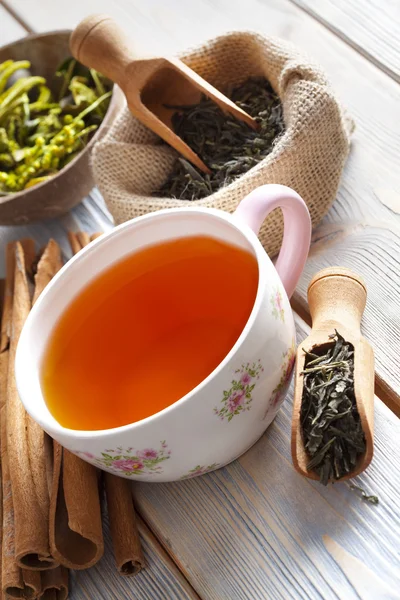 Taza de té y hojas de té secas en tablones de madera — Foto de Stock