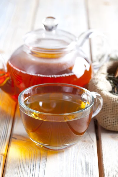 Ahşap plakalar üzerinde bardak çay, çaydanlık ve kuru çay yaprakları