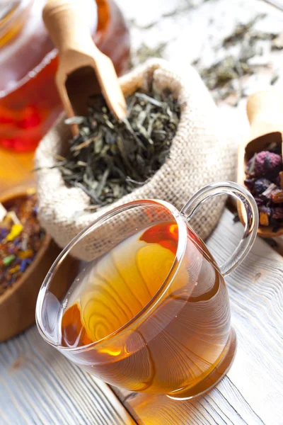 Cup of tea, teapot and mix of assorted tea leaves on wooden tabl — Stock Photo, Image