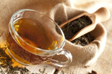 Ahşap masa üzerinde bardak çay ve çay yaprakları