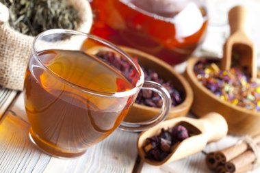 Fincan çay, çaydanlık ve çeşitli çay karışımı ahşap tabl bırakır