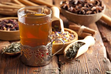 Ahşap masa üzerinde bardak çay ve çay yaprakları