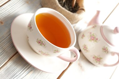 Ahşap masa üzerinde bardak çay, çaydanlık ve kuru çay yaprakları 