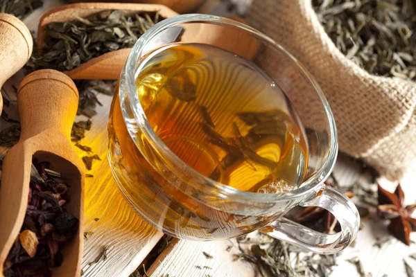 Šálek čaje a směsice nejrůznějších čajové listy na dřevěný stůl — Stock fotografie