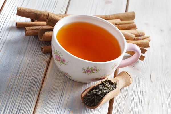 Tazza di tè, foglie di tè essiccate e bastoncini di cannella — Foto Stock