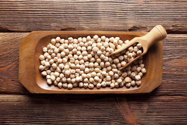 Pois chiches dans un bol sur fond en bois — Photo