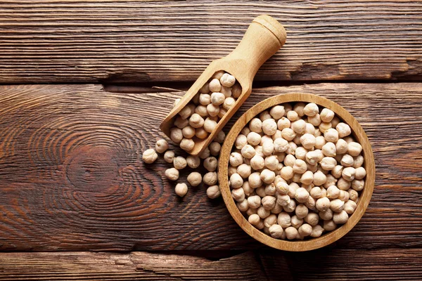 Chickpeas in bowl on wooden table — Stock Photo, Image