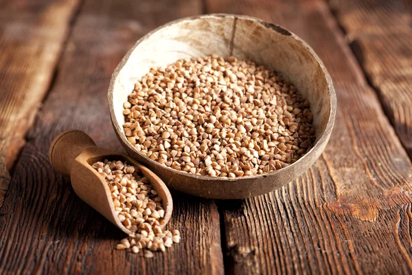 Buckwheat in scoop and bowl on wooden table — Stock Photo, Image