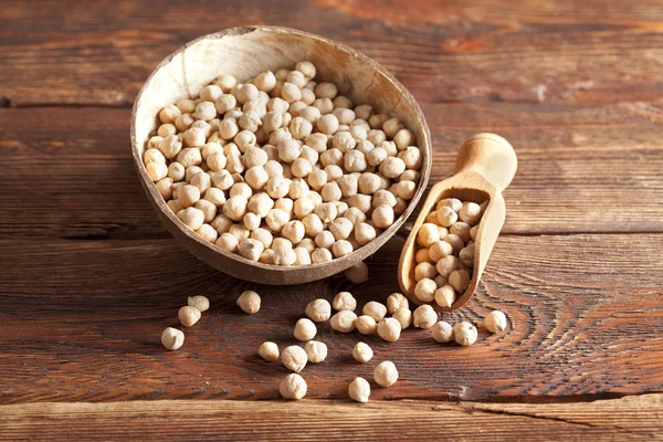 Pois chiches dans un bol et une cuillère sur une table en bois — Photo