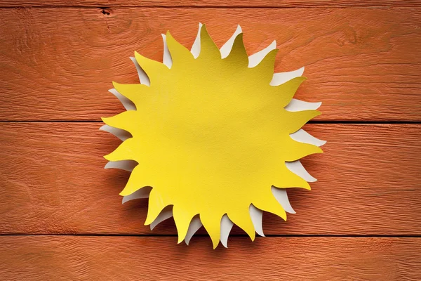 Paper sheet in the shape of the sun on wooden background — Stock Photo, Image