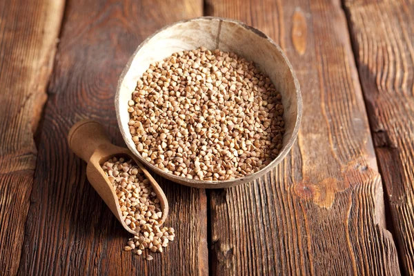 Buckwheat in scoop and bowl on wooden table — Stock Photo, Image