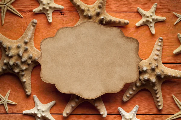 Folha de papel em branco e estrela-do-mar em fundo de madeira — Fotografia de Stock