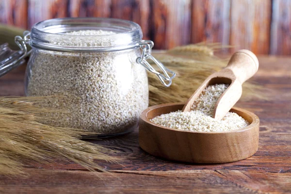 Buckwheat in bowl and jar on wooden table — Stock Photo, Image